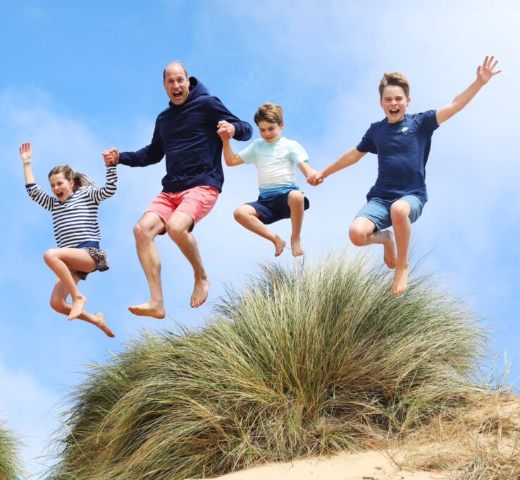 Prinz William springt mit den Kindern Charlotte, Louis und George in den Sand.